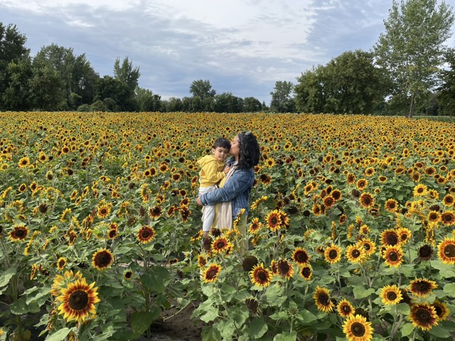 Kris Daria holding and kissing her son Jayden in a sunflower field